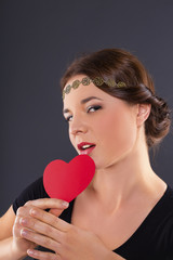 Young woman with red heart on black background