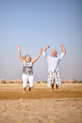 Fototapeta na wymiar Mature couple jumping on beach