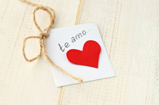 Paper message with red heart. Handwritten text "te amo" in spanish , means "I love you".