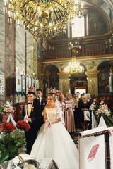 Religious blonde bride and handsome groom in crowns in church at