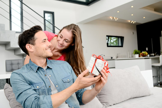 cheerful young couple offering a gift present for birthday or valentines day