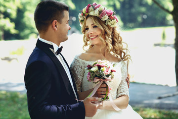 Handsome happy groom and smiling bride in elegant white dress in
