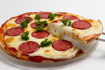 Sliced pepperoni pizza with herb on white background