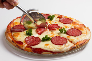 Man's hand with a knife cut the pizza on white background