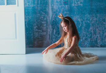 A child dressed as a princess, sitting on the floor, straightens