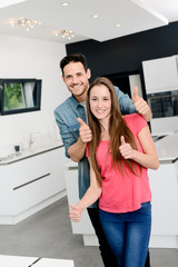 cheerful young couple happy in their new modern design house showing thumbs up