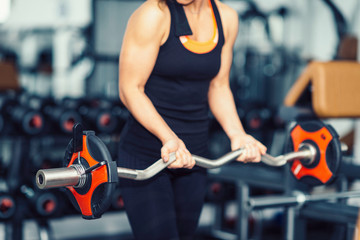 Woman exercising in gym with barbell weights
