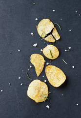 Fototapeta na wymiar Chips with salt and rosemary on black background