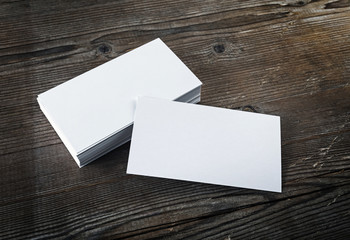 Photo of blank white business cards on a dark wooden background. Mock-up for branding identity. Blank template for design presentations and portfolios. 