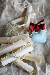 Wedding vintage paper invitation scrolls and blue ceramic heart with red bow on a sackcloth.