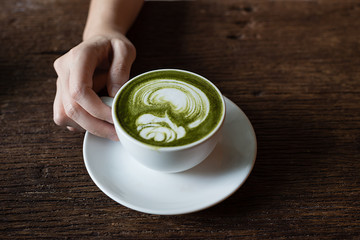 hand holding matcha gren tea latte with rose pattern latte art