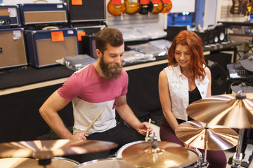 happy man and woman playing cymbals at music store