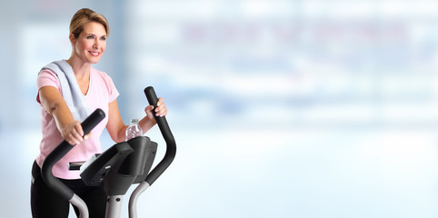 Mature woman doing exercise on elliptical trainer.