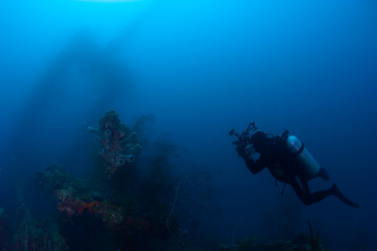 Underwater photographer exploring wreck ship in the deep.