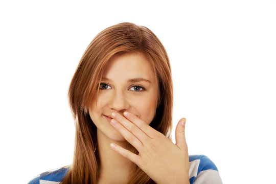 Teenage woman giggles covering her mouth with hand