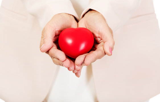 Elderly woman holding heart model on open palms