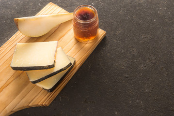 Some sliced typical Pecorino cheese with a sliced pear and a little jam jar