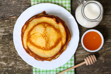 sweet pancakes with honey on wooden background 