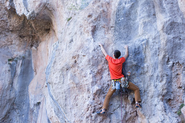 Young male climber hanging by a cliff