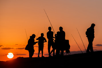 Fototapeta na wymiar Silhouettes of fishermen at sunset