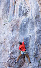 Fototapeta premium Young male climber hanging by a cliff