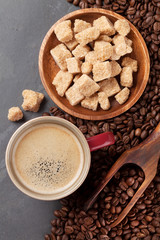 Coffee cup, beans and brown sugar on stone table