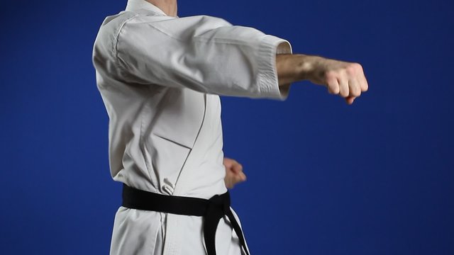 An athlete with a white dress with a black belt doing the right punch