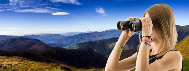 young woman with binoculars in the mountains