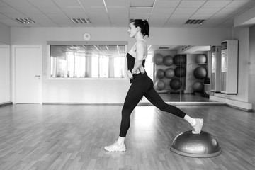 Fototapeta na wymiar Beautiful young woman doing fitness in the gym. Girl uses fitball exercise, expander, hemisphere.
