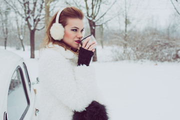 Young woman drinking hot tea or coffee outdoor, vintage winter vacation concept