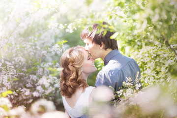 Love couple standing among blooming apple tree