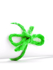 Handmade green rope node tied on white paper scroll isolated