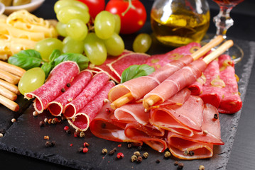 grissini stick bread with ham on black board with appetizers