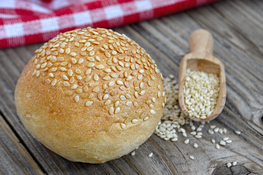 Bun with sesame seeds on wooden background