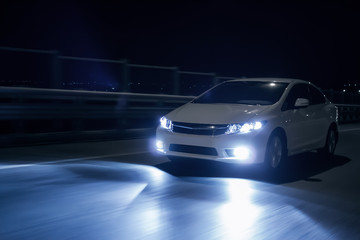 Obraz premium Car with xenon headlights fast drive on road at nigh