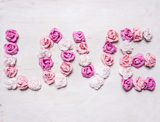 word love made of paper roses, decorations for Valentine's Day  on wooden white rustic background top view close up