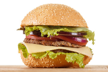 Traditional American cheeseburger. Meat, bun and vegetables close up