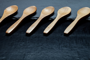 Wooden spoons on a plate of slate on a black background. Toned