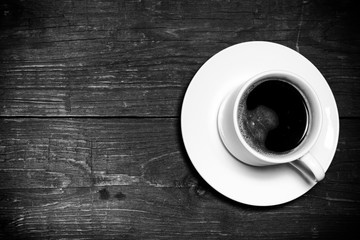White cup of coffee on old wooden table. Toned