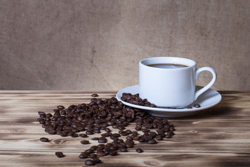 Coffee beans and coffee in white cup on wooden table opposite a