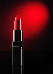 Red lipstick on black, reflective, mirror background. Background for cosmetic or beauty advertising.