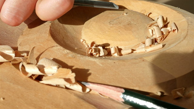 Wood carving - Human hand chiseling a piece of wood
