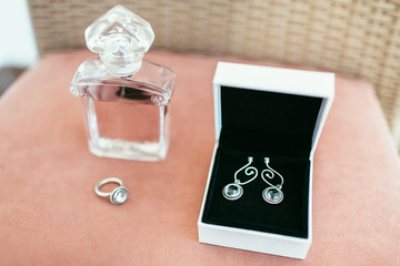 bride ear-rings in white box and ring with perfume on wedding da
