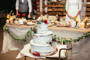 rustic wedding cake on wedding banquet with red rose and other f - 101070170