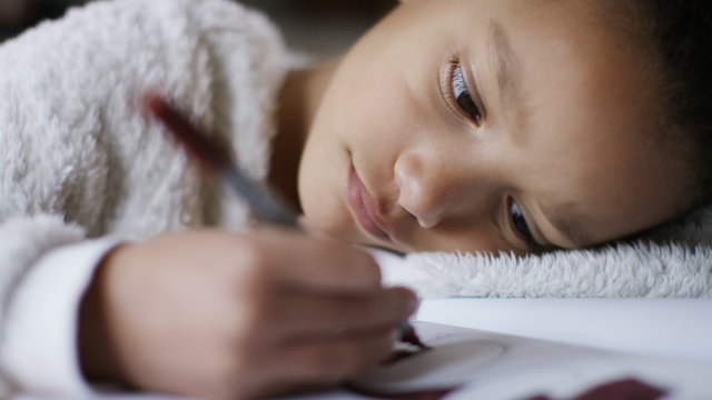 Young girl concentrating on her colouring in book