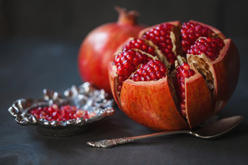 Juicy pomegranates,whole and broken on a grey wooden table. Vintage style