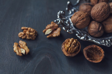 Walnuts in a bowl, whole and chopped on grey wooden table. Vintage style