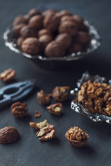 Walnuts in a bowl, whole and chopped on grey wooden table. Vintage style