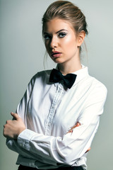 Beautiful young woman wearing a shirt and bow tie against a gray background