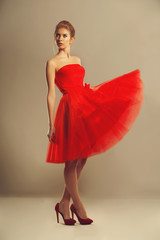 Confident model in a red flowing dress in studio